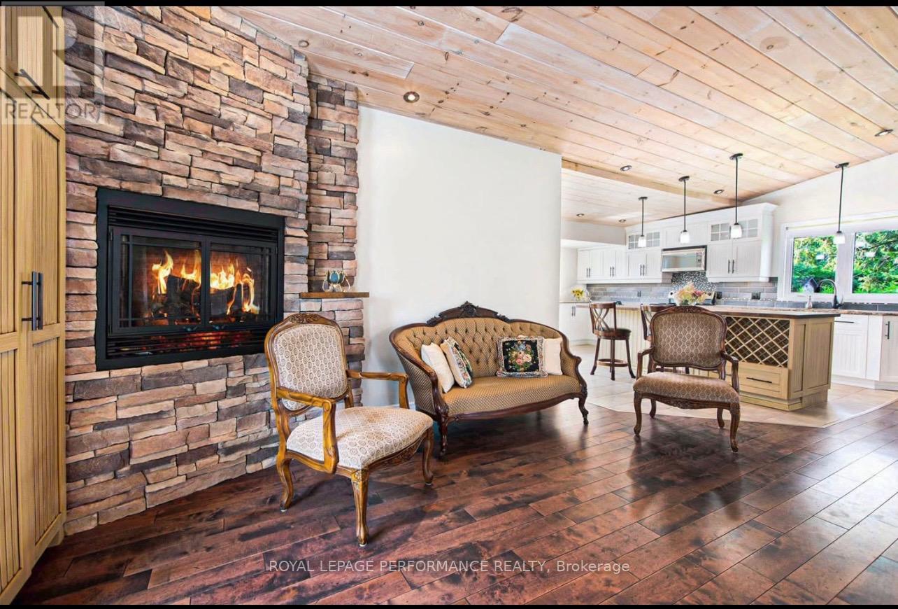 A living room with a stone fireplace and wooden floors.
