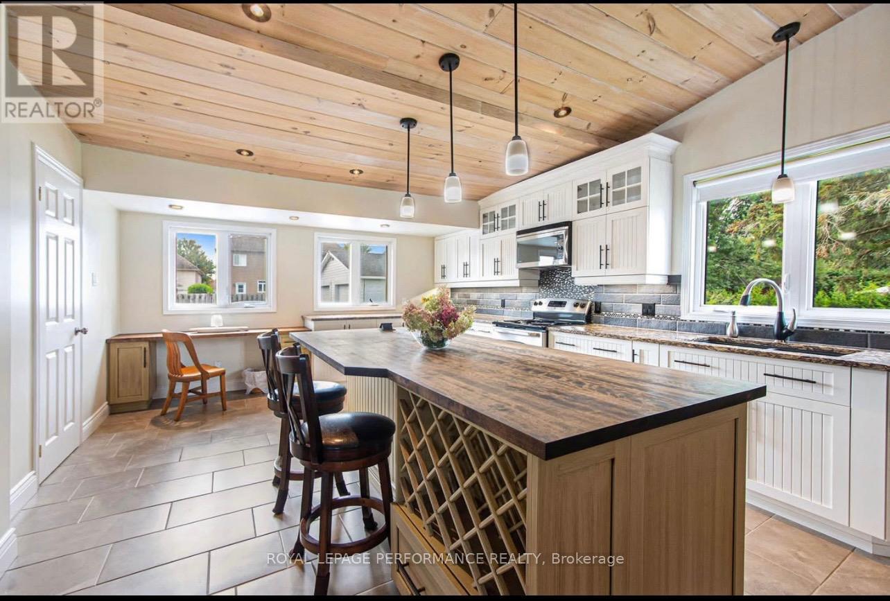 A kitchen with a wooden ceiling and a large island with a bar stool.