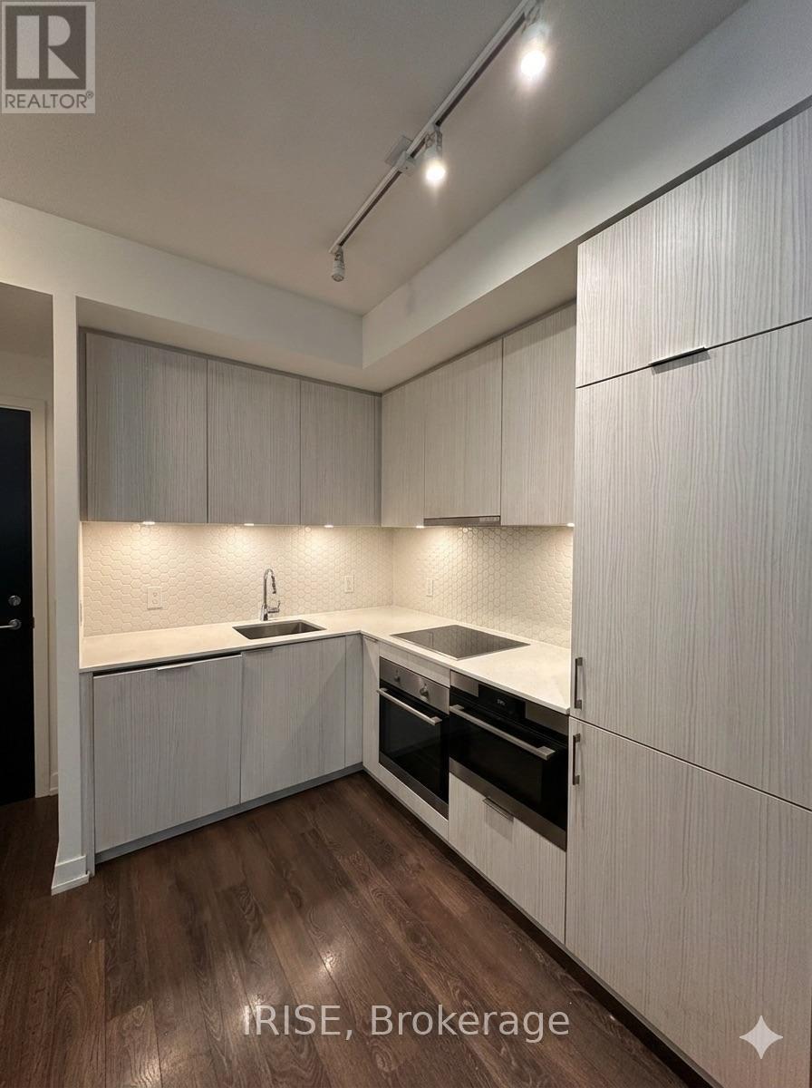 A modern kitchen with white cabinets and a wooden floor.