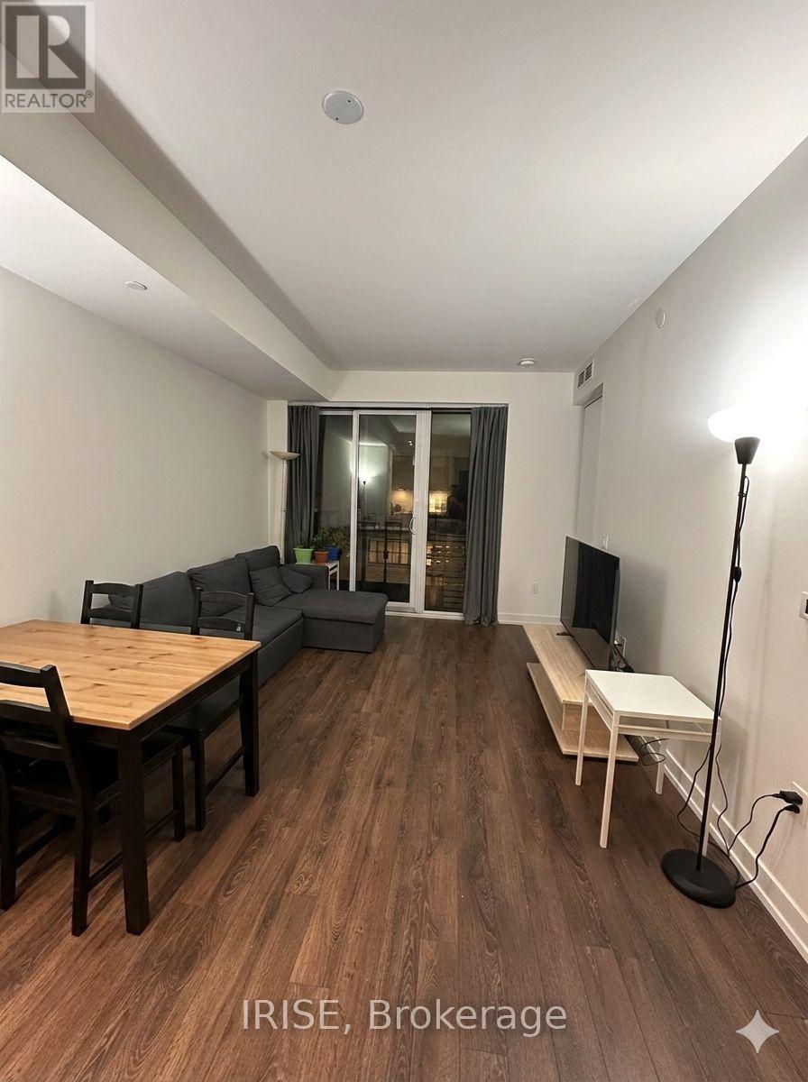 A living room with a wooden floor and a dining table with chairs.