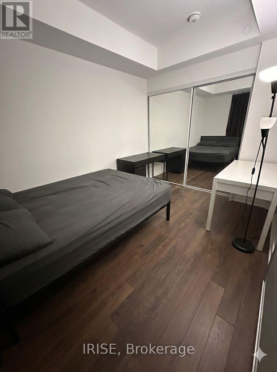 A bedroom with a bed, desk, and mirror.