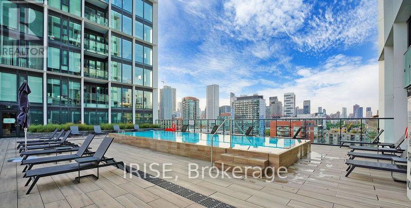A rooftop pool area with lounge chairs and a view of the city skyline.
