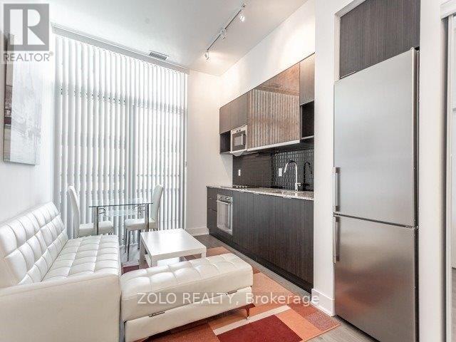 A modern kitchen with a white couch and a refrigerator.