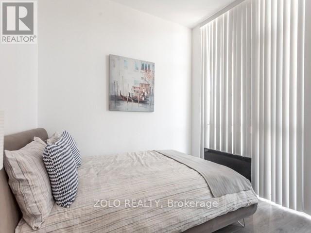 A bedroom with a bed, pillow, and a painting on the wall.