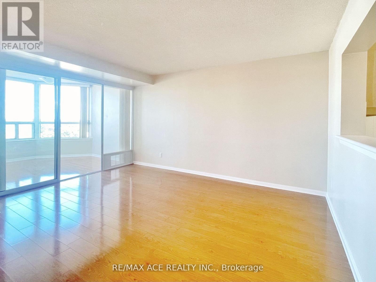 A spacious room with wooden flooring and large windows.