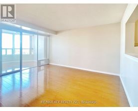 A spacious room with wooden flooring and large windows.