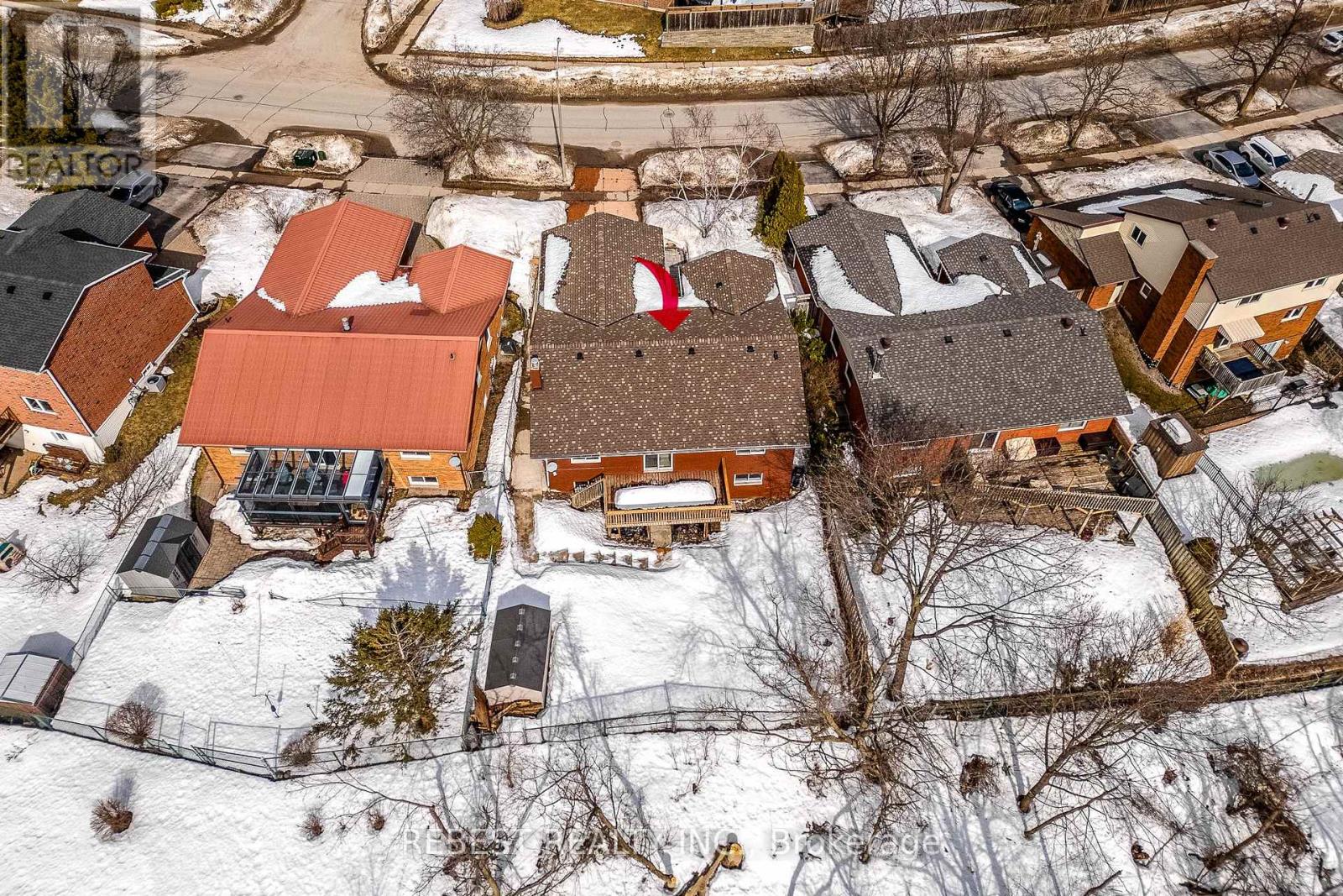 A bird's eye view of a snowy residential area with houses and bare trees.