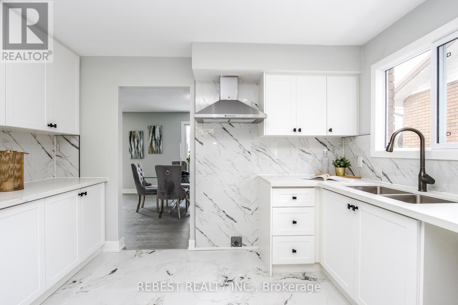 A modern kitchen with white cabinets and a marble backsplash.