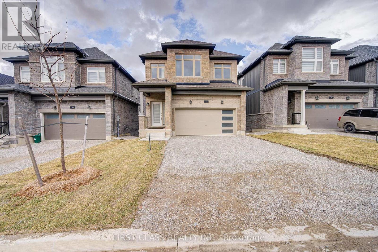 A large, modern house with a grey front yard and a driveway.