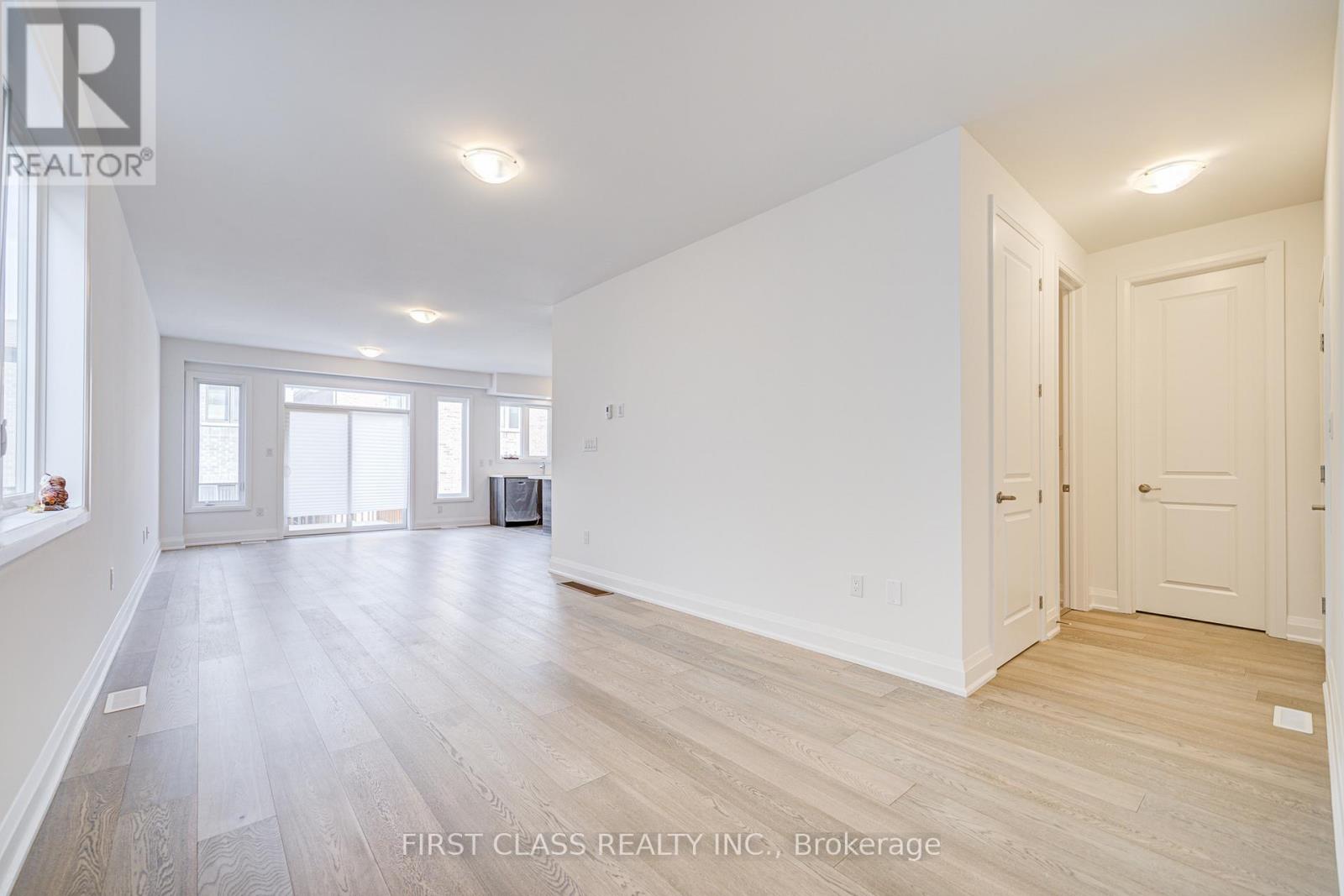 A spacious room with wooden flooring and white walls.