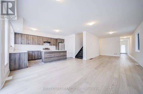 A spacious living room with a kitchen area in the background.