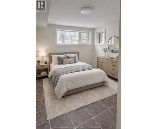 A bedroom with a bed, nightstand, and a mirror.