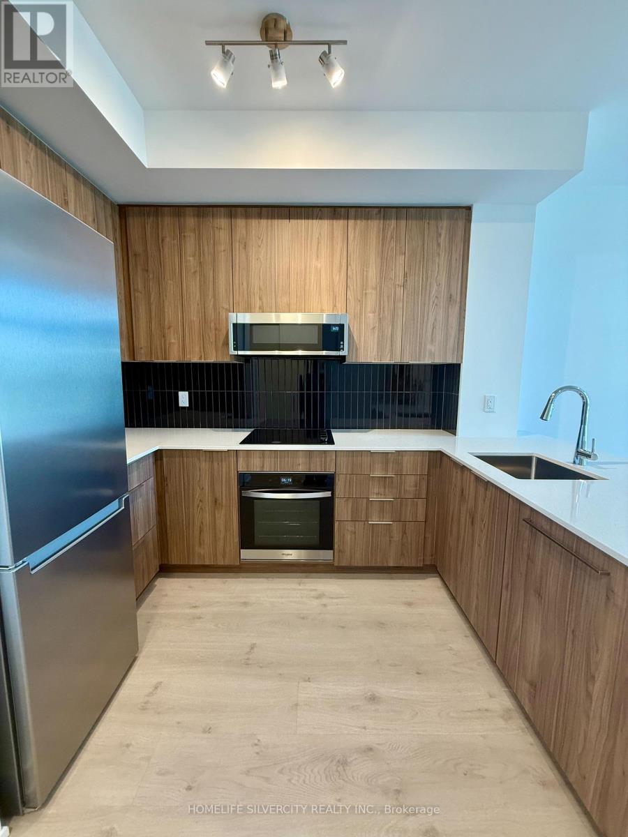 A kitchen with wooden cabinets and a stainless steel refrigerator.