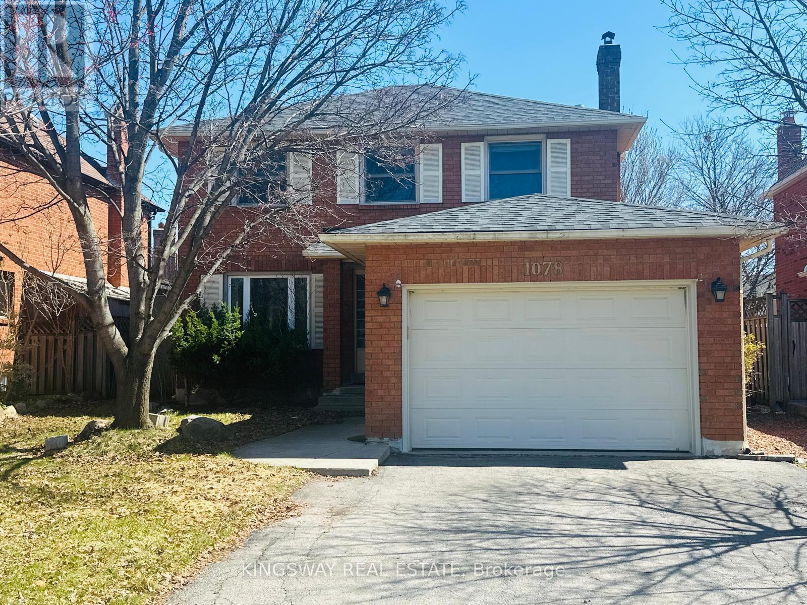 A house with a white garage door and a brick wall with the number 107 on it.