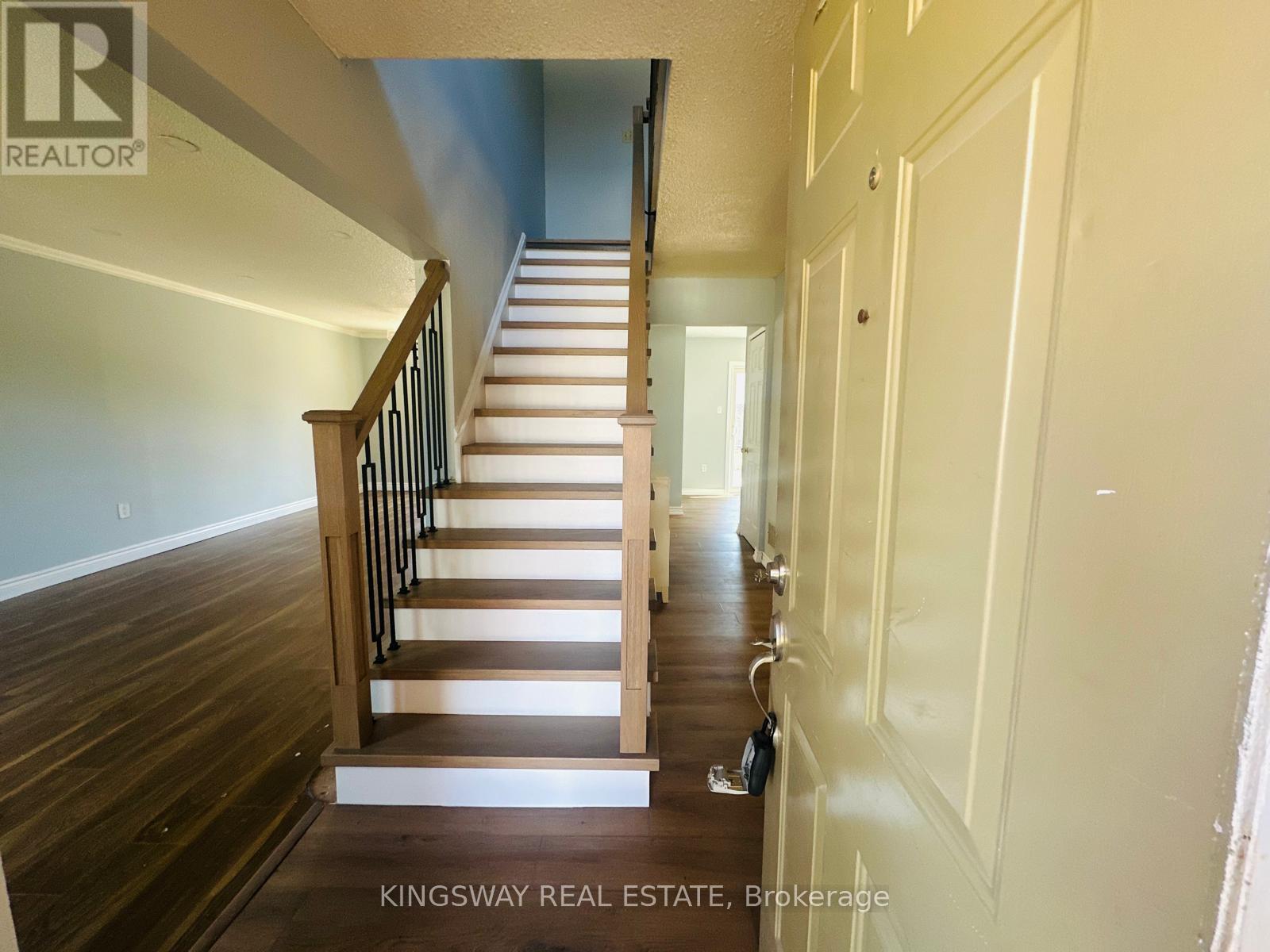 A staircase with a wooden handrail and a white wall.