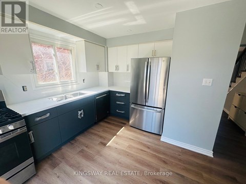 A kitchen with a stainless steel refrigerator and dark wood flooring.