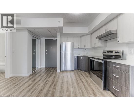 A modern kitchen with a stainless steel refrigerator and wooden flooring.