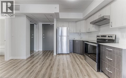 A modern kitchen with a stainless steel refrigerator and wooden flooring.