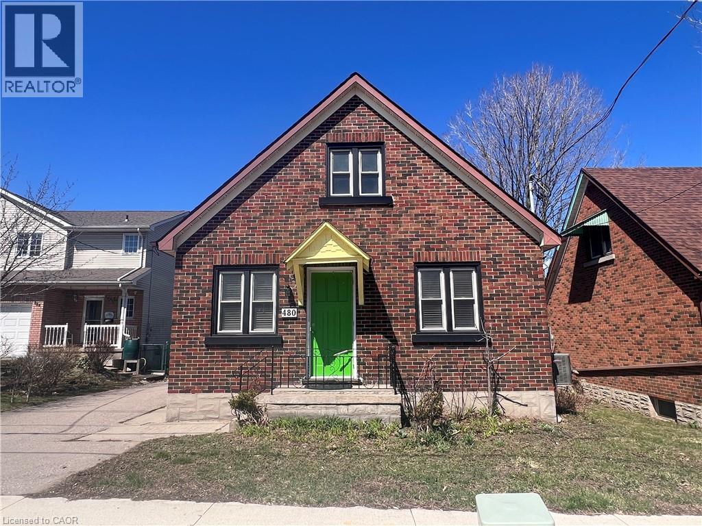 A red brick house with a green door and a yellow window frame.
