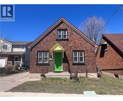 A red brick house with a green door and a yellow window frame.