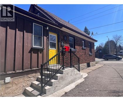 A house with a yellow door and a black railing on the stairs.