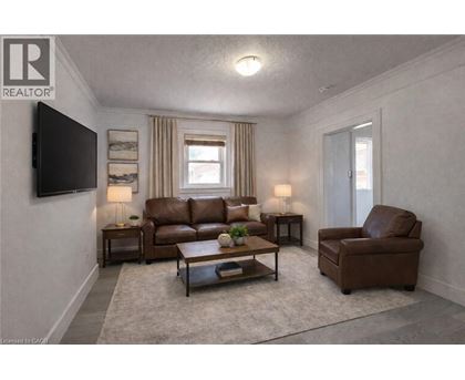 A living room with a brown leather couch and a grey rug.