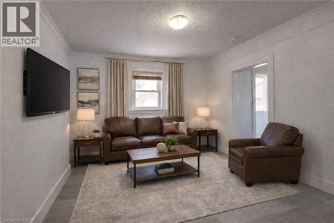 A living room with a brown leather couch and a grey rug.