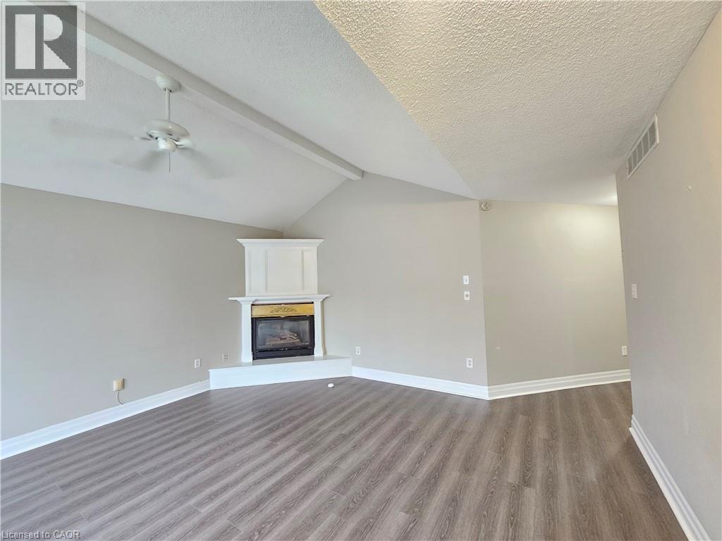 A large empty room with a fireplace and wood flooring.