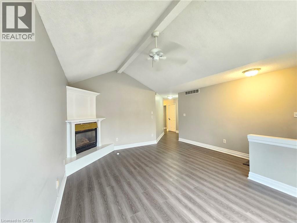 A spacious room with a fireplace and wood flooring.