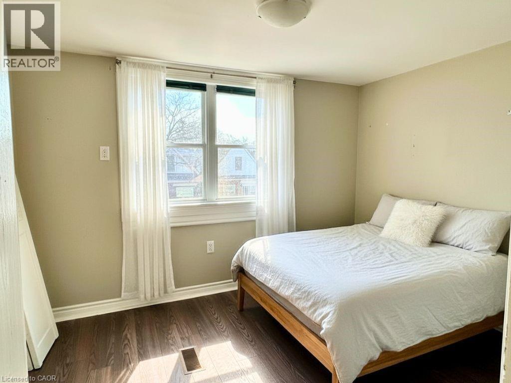 A bedroom with a bed, window, and wooden flooring.