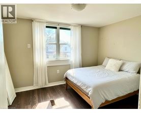 A bedroom with a bed, window, and wooden flooring.