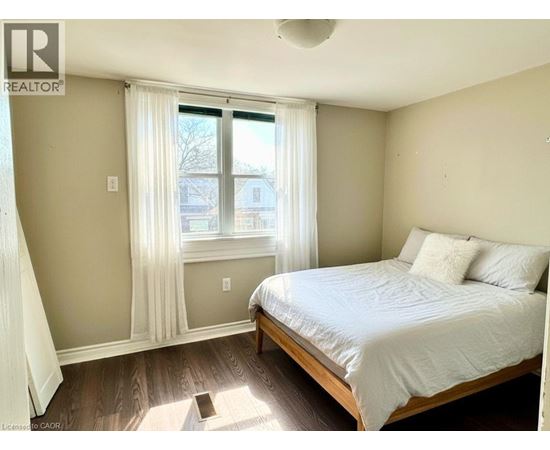 A bedroom with a bed, window, and wooden flooring.