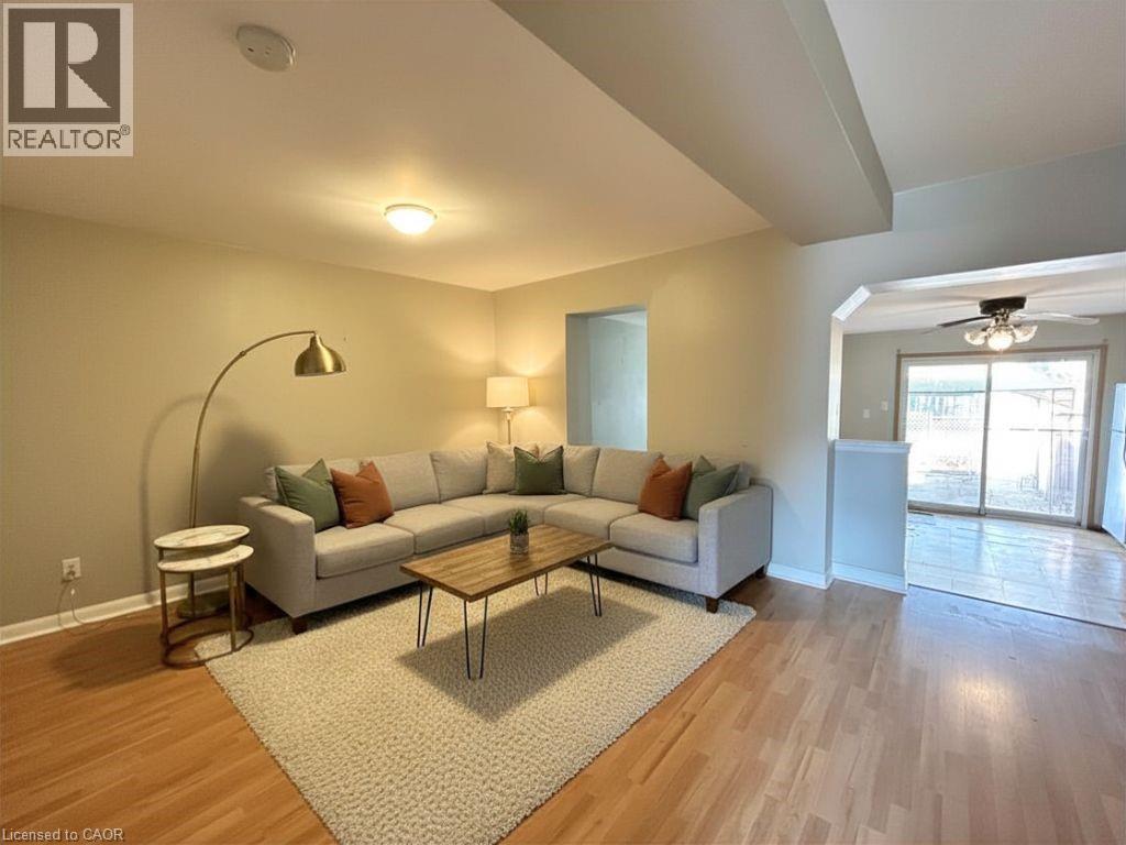 A living room with a white couch and a grey rug.
