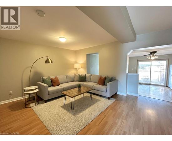 A living room with a white couch and a grey rug.
