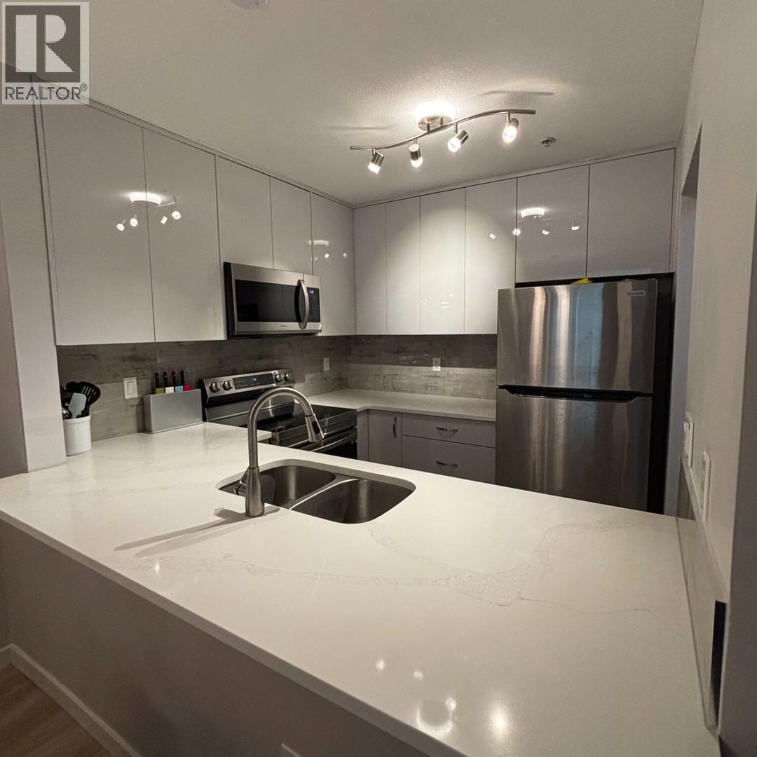 A modern kitchen with a stainless steel refrigerator and a white countertop.