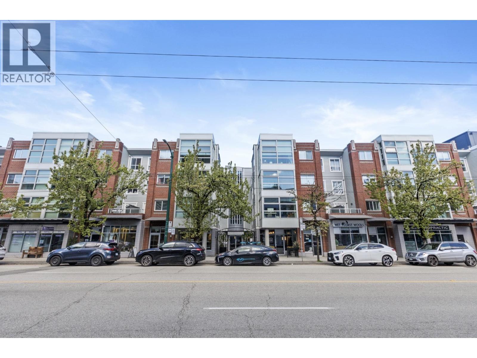 A row of modern apartment buildings with cars parked in front.