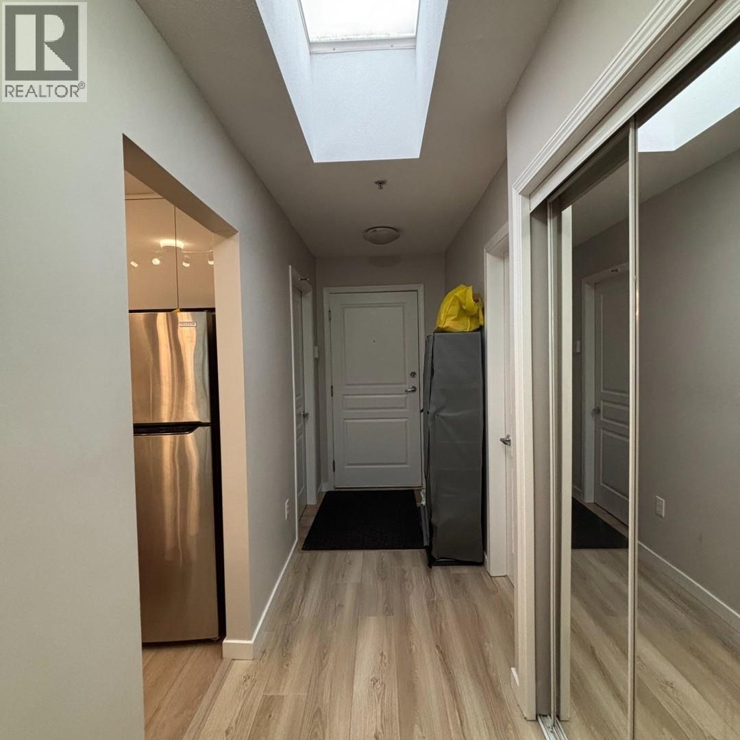 A hallway with a skylight, a door, and a refrigerator.