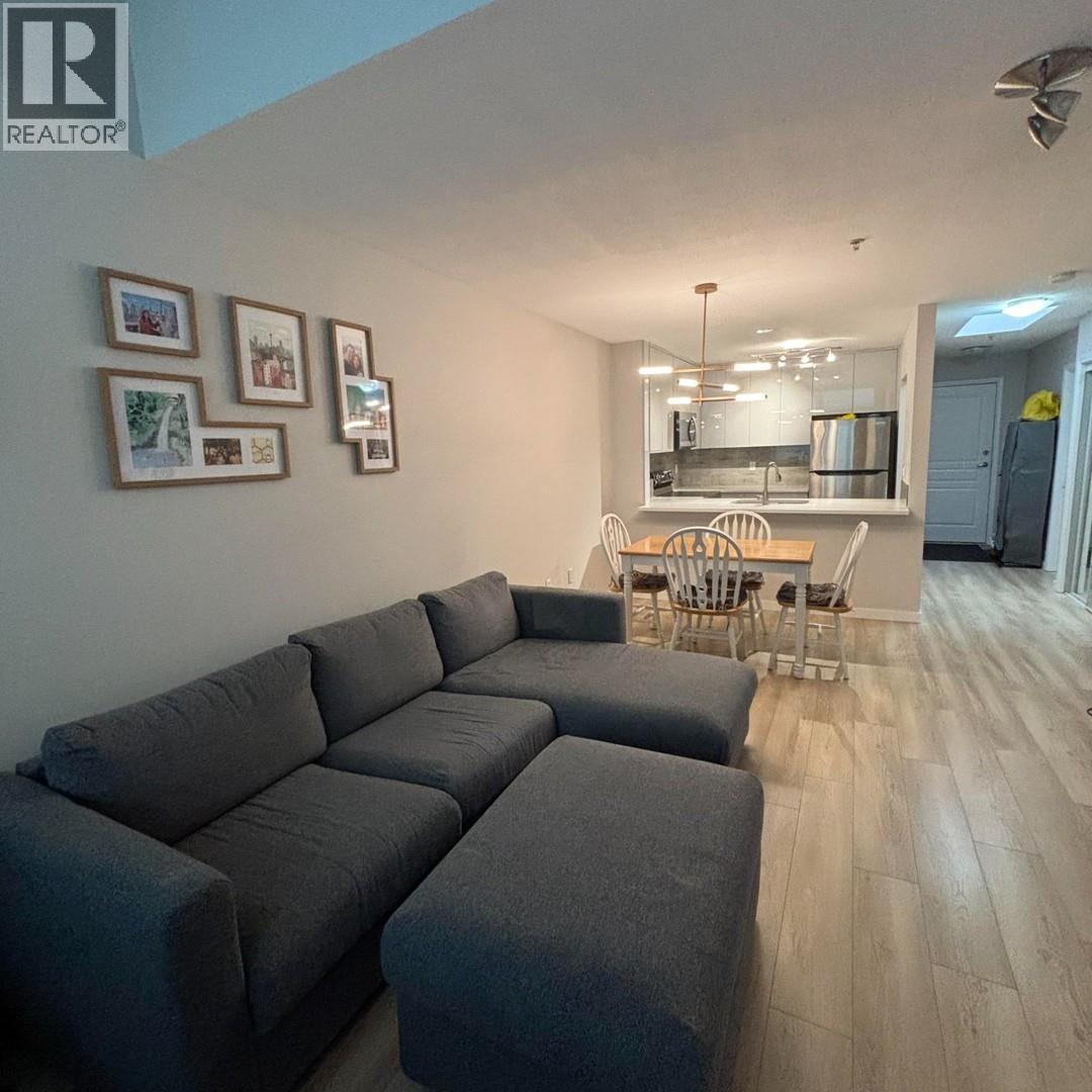A grey sectional sofa in a living room with a bar and framed pictures on the wall.