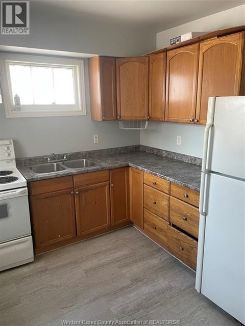 A kitchen with wooden cabinets and a white fridge.