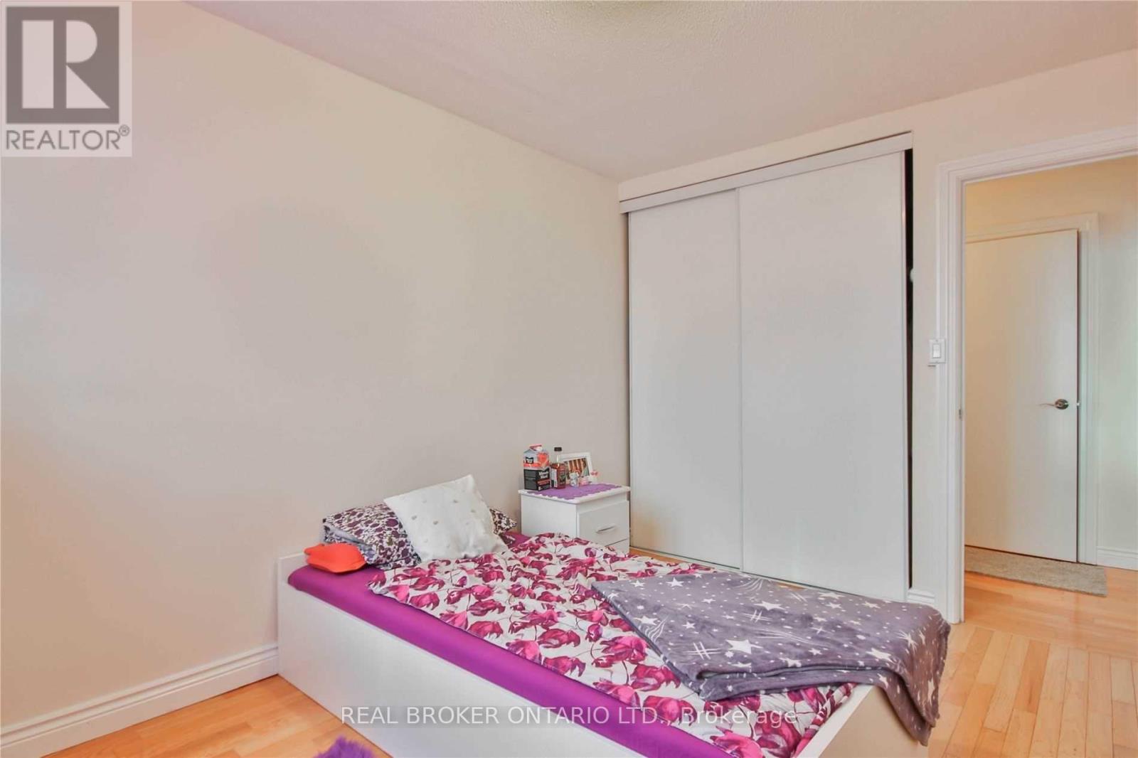 A bedroom with a bed, pillows, and a blanket with a floral pattern.