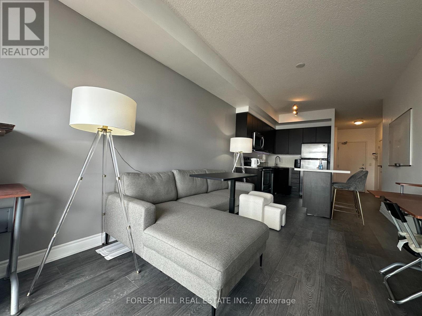 A well-lit living room with a grey sofa and a wooden floor.