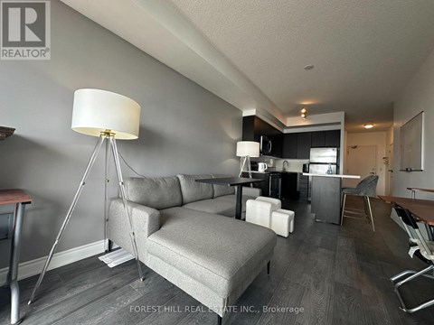 A well-lit living room with a grey sofa and a wooden floor.