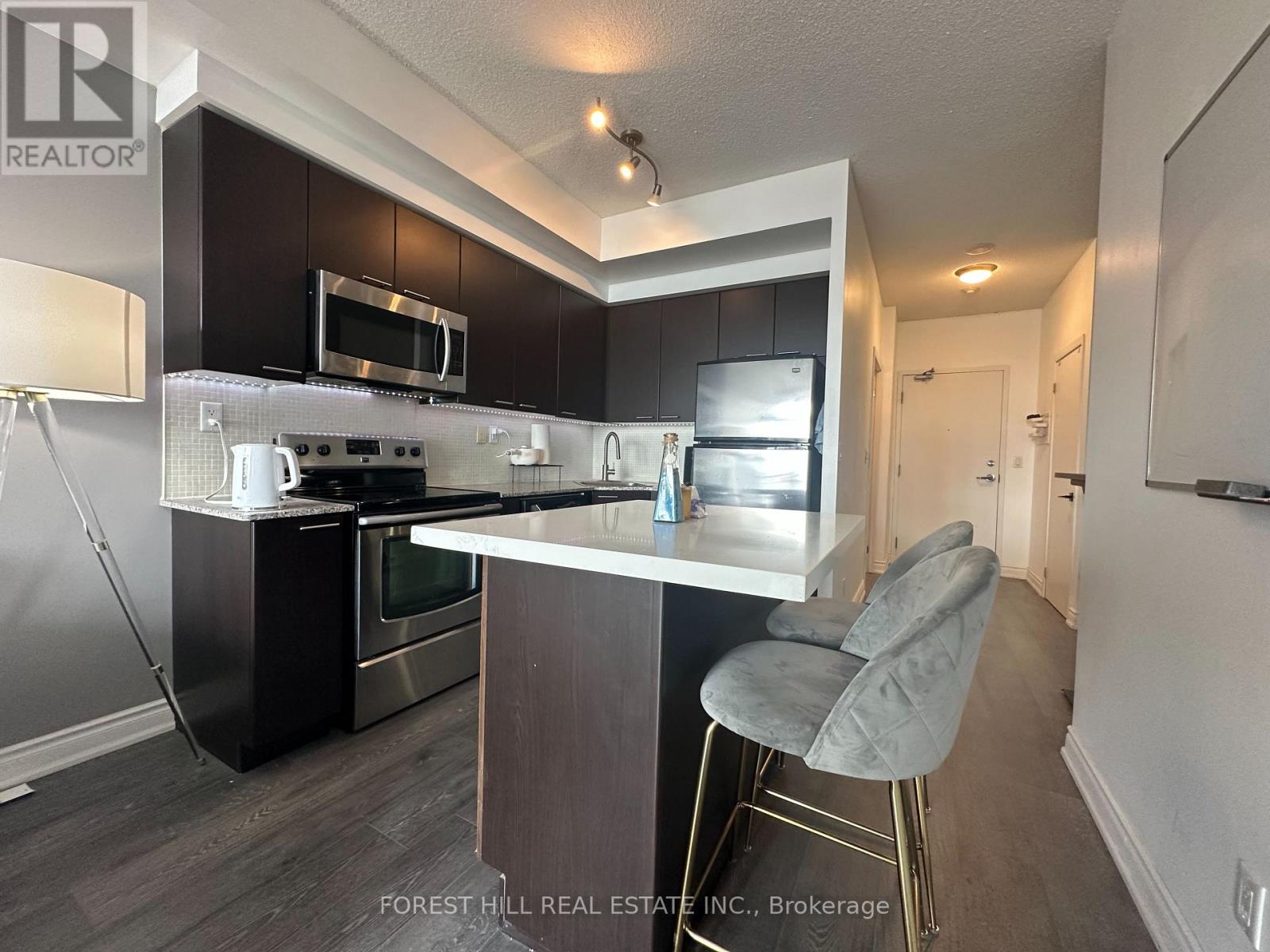 A modern kitchen with dark wood cabinets and stainless steel appliances.