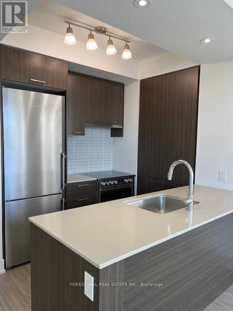 A modern kitchen with a stainless steel refrigerator and a sink.