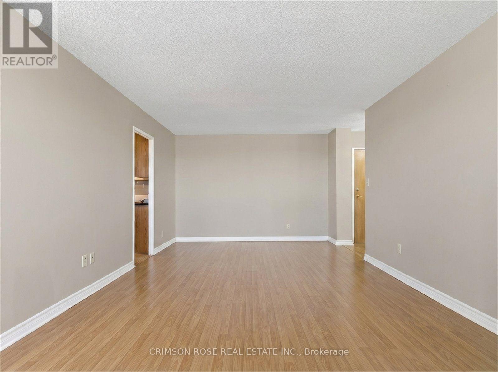 A spacious room with wooden flooring and white walls.