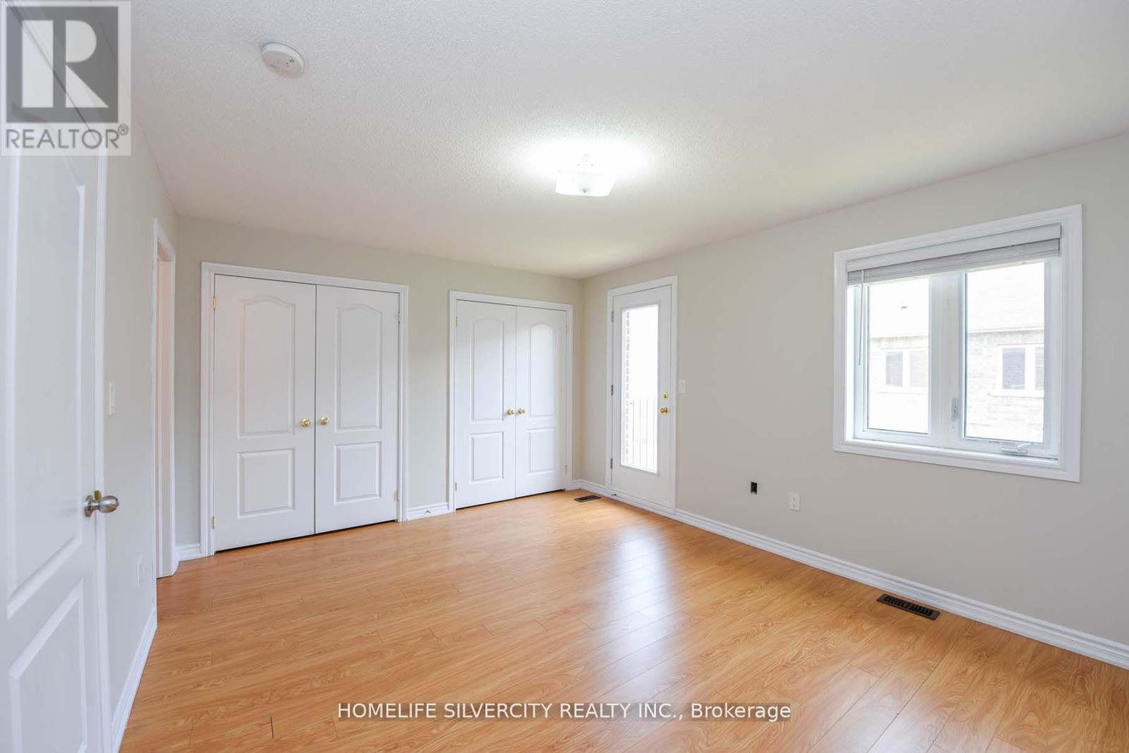 A room with wooden floors and white walls, with a window on the right side.