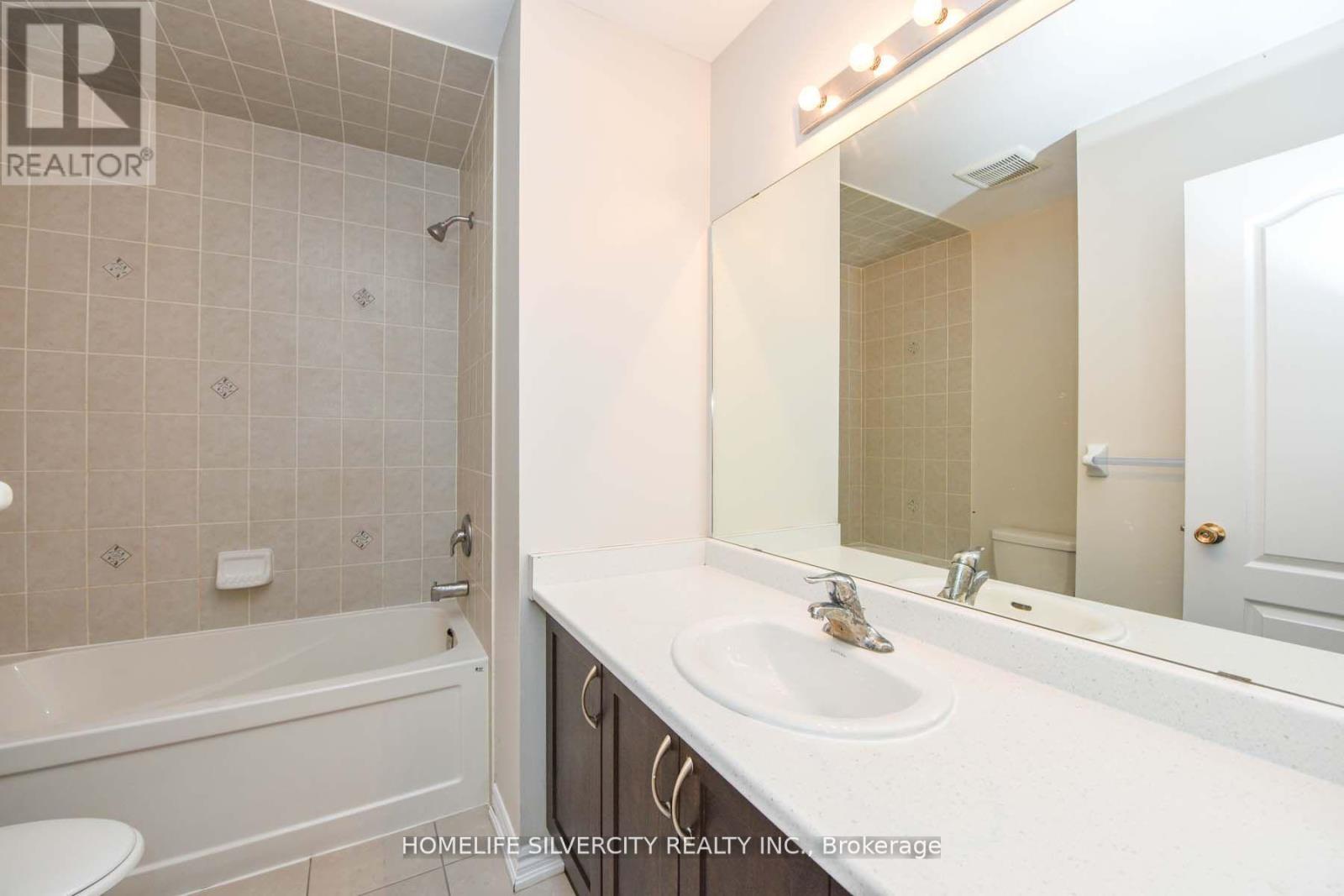 A bathroom with a white tub, sink, and tiled walls.