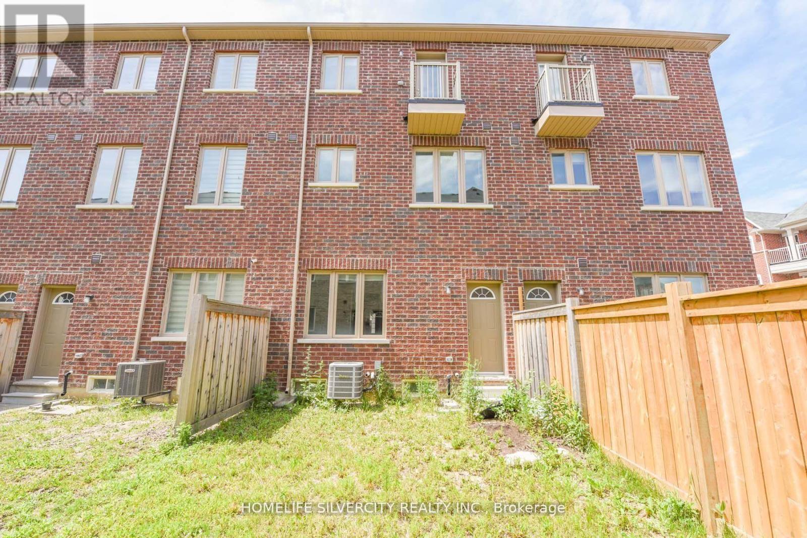 A red brick apartment building with a wooden fence in front.