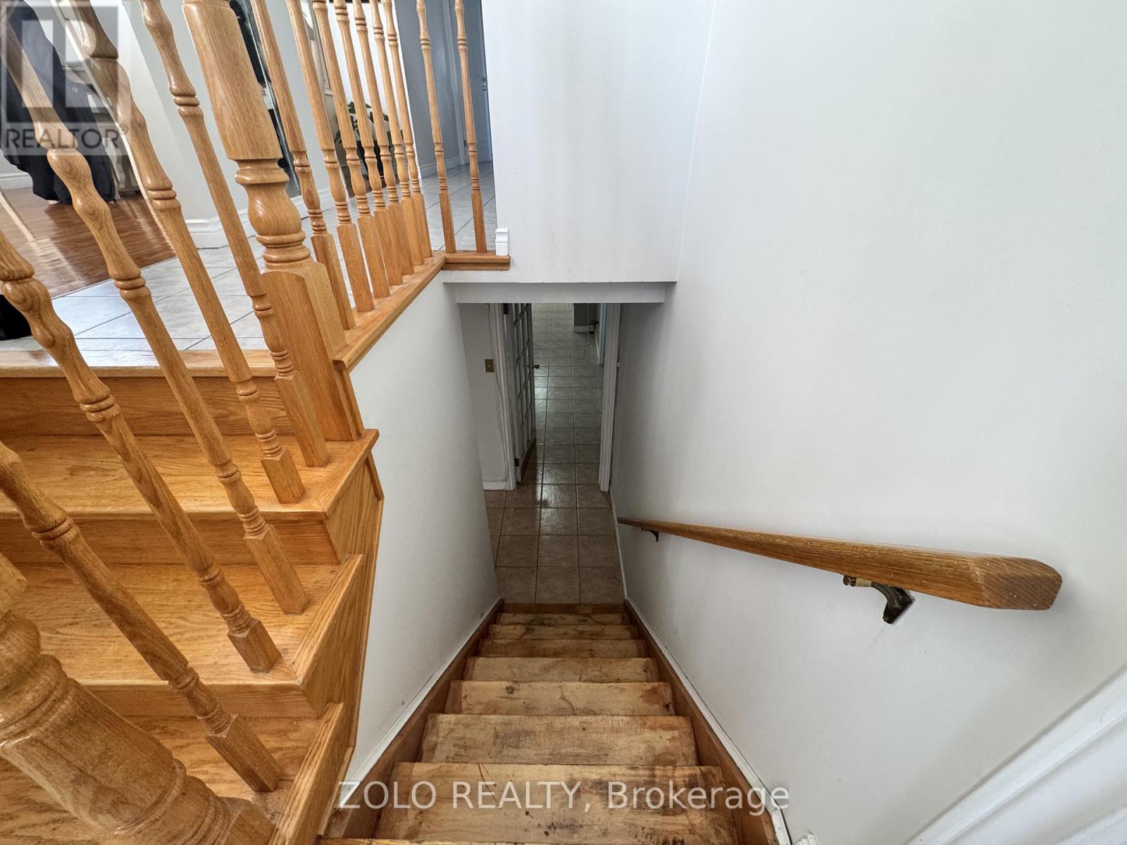 A wooden staircase with a white wall and a glass door in the background.