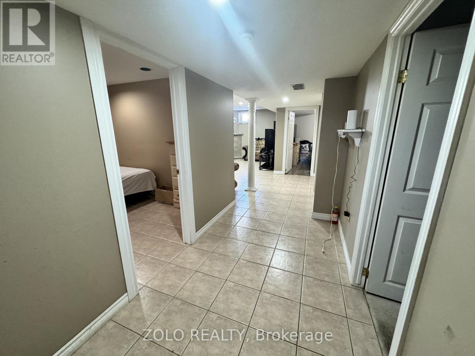 A hallway with tiled floors and white walls, leading to a bedroom.